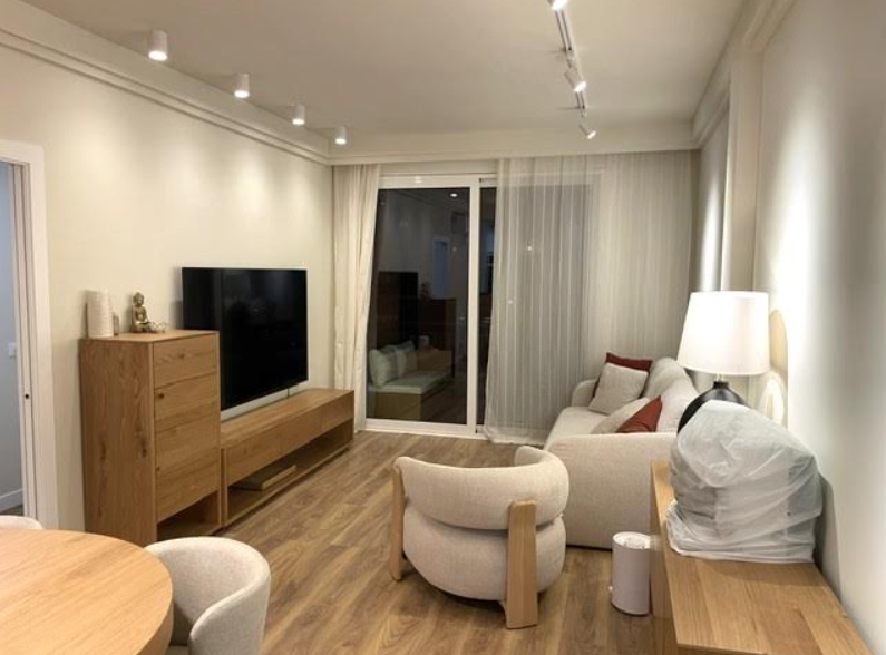 Salón reformado con suelo de madera, muebles de roble y iluminación moderna