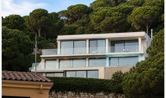 Fachada principal de la vivienda con grandes ventanales y entorno arbolado