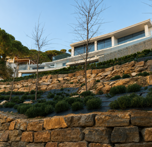 Vivienda de líneas horizontales sobre muros de piedra natural y vegetación mediterránea