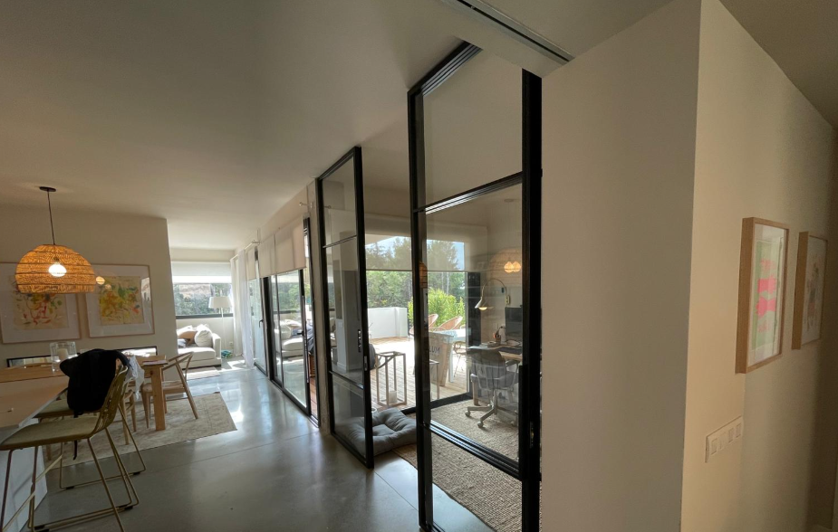 Interior con puertas correderas de cristal y acero negro, salón y comedor