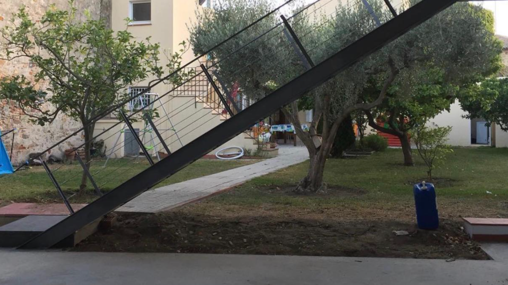 Estructura metálica inclinada de la escalera de acceso en el jardín, junto a los olivos