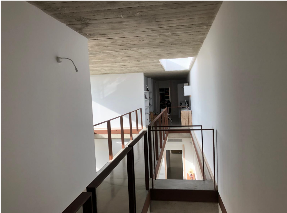 Escalera y doble espacio con lucernario y techo de hormigón visto