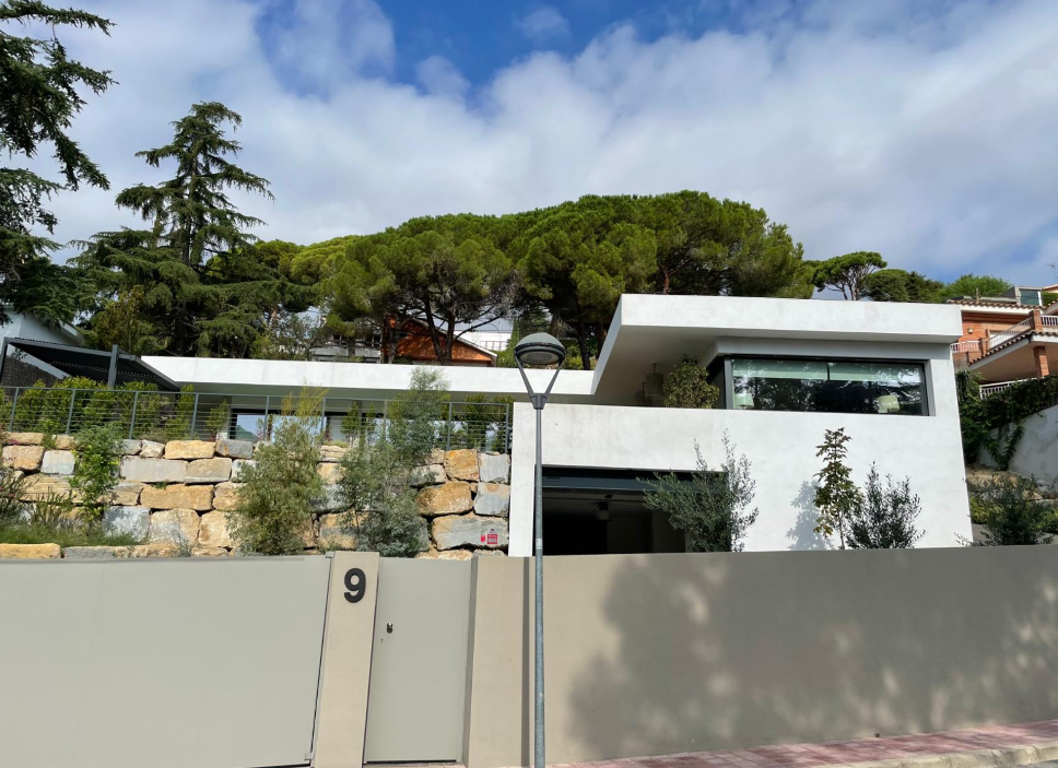 Vista exterior de la vivienda desde la calle, con muro de piedra y acceso