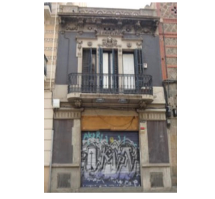 Fachada de la casa Monsech en Sants antes de la rehabilitación, con local cerrado y grafitis