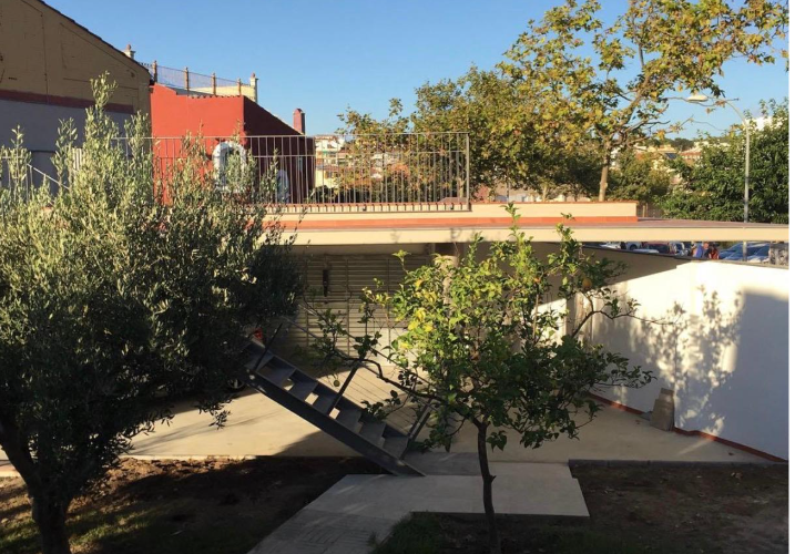 Porche y parking de obra nueva con cubierta plana, integrado en el jardín con olivos y cítricos