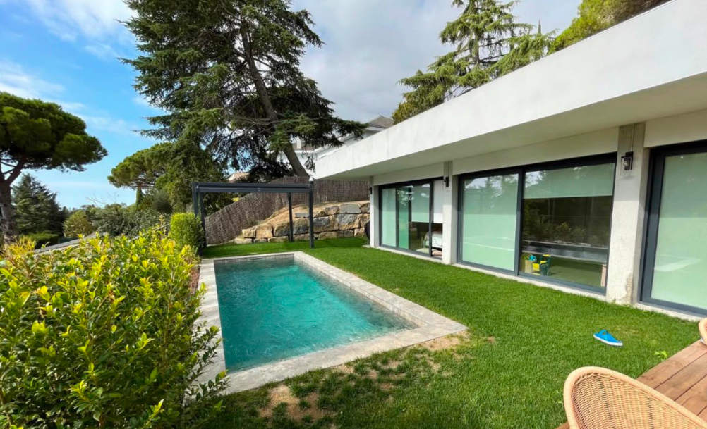 Jardín con piscina, césped y fachada de cristal de la vivienda
